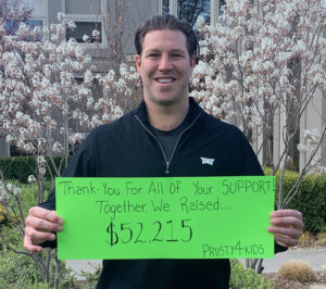Brandon Prust holding a sign that says our community raised over $52,000 for the Family Assistance Program.