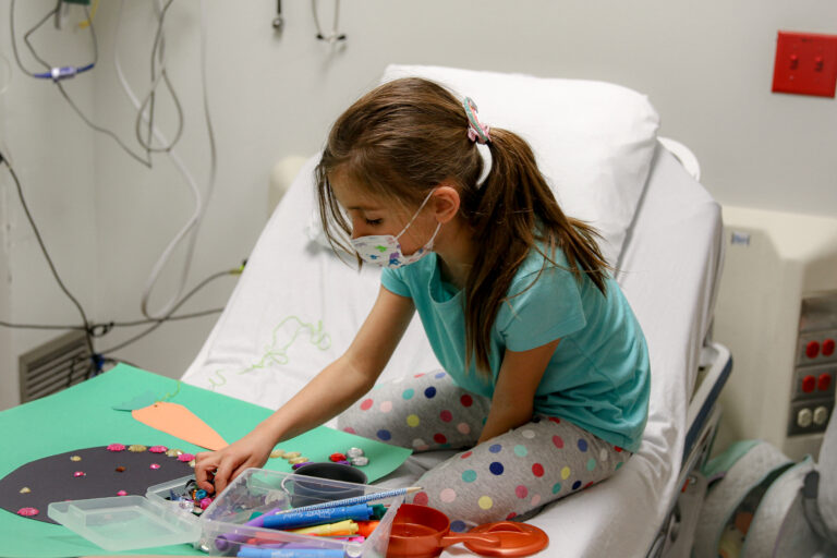 A child making a craft in her hospital bed