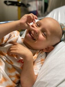 A paediatric cancer patient smiling in bed.