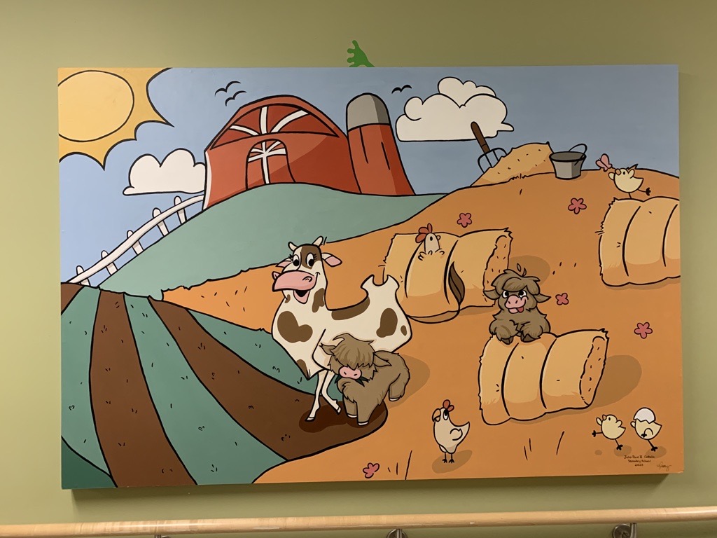 A farm scene mural featuring a cow in a hay field.