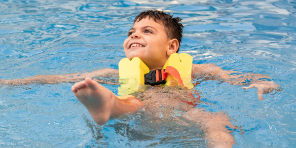 A child swimming while wearing a life jacket