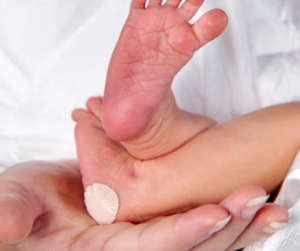 Infant's feet with a bandage covering an injection mark on the left heel