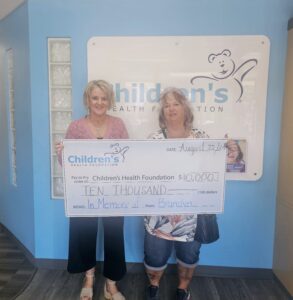 Two women hold up a large cheque for a $10,000 donation to Children's Health Foundation.