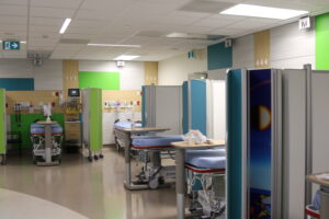 A view of some of the beds in the new expansion to the emergency room at Children's Hospital, LHSC. Four beds are visible, with bright green panels on the walls.