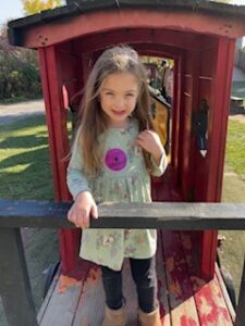 A young girl poses on a piece of playground equipment.